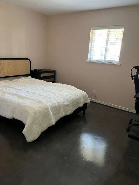 Furnished bedroom with queen bed, nightstand, window, and work chair